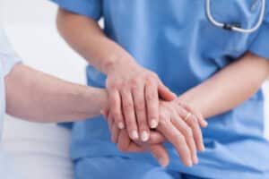 Close up of a nurse touching hand of a patient - Advantage Medical Professionals